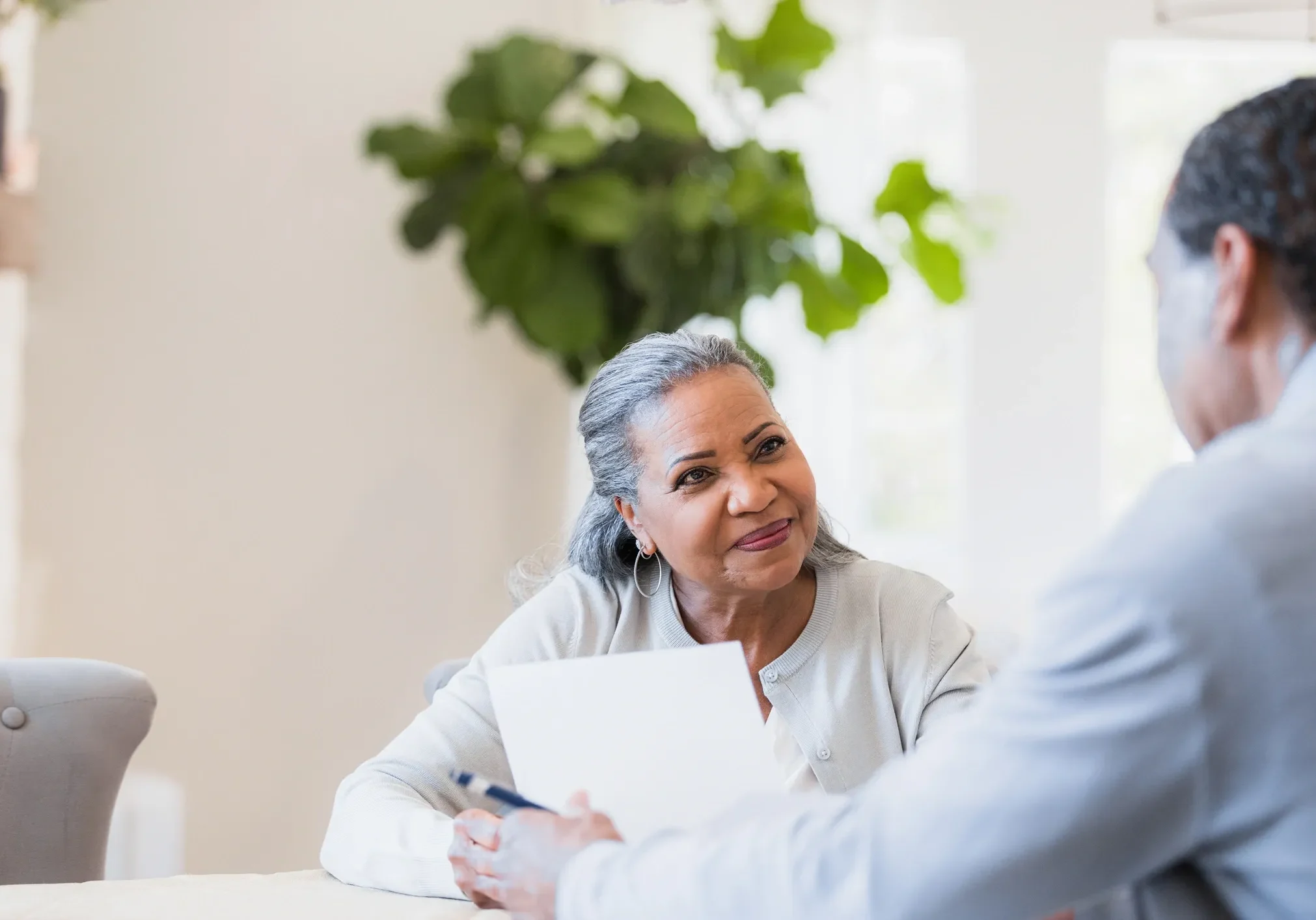 Older adults discussing paperwork at table.