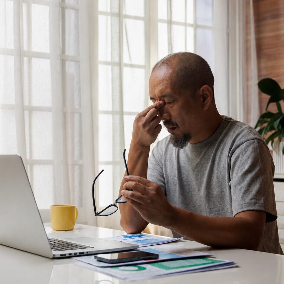Man at desk with laptop, looking stressed.